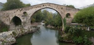 Vista panorámica del puente romano de Cangas de Onis, con la réplica de la Cruz de la Victoria colgando del mismo